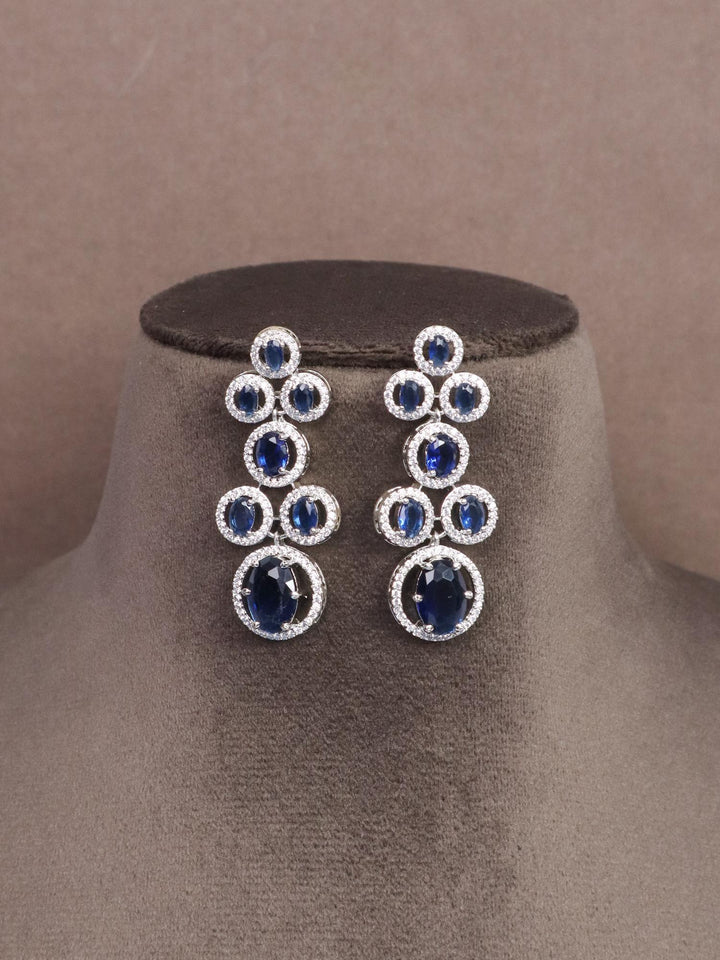 A closeup image of Dazzle Blue Sapphire Diamond Earrings by Live Some India on a brown dummy 