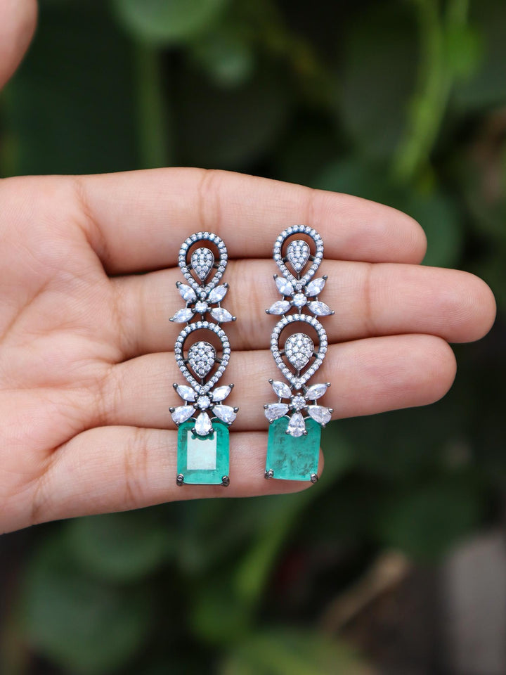 Emerald Doublet Dangle Earrings by Live Some India on hands with Natural Green Leaves background