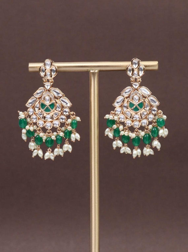 A closeup image of Esha Green Kundan Polki Dangler Earrings by Live Some India on a brown background