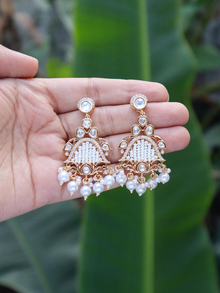Ethnic Kundan Polki Designer Earrings with Pearl Drops by Live Some India on hands with natural green leaves in the background