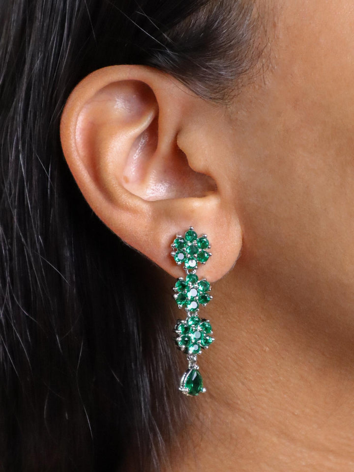 A closeup image of a girl wearing Flora Emerald Diamond Earrings by Live Some India 