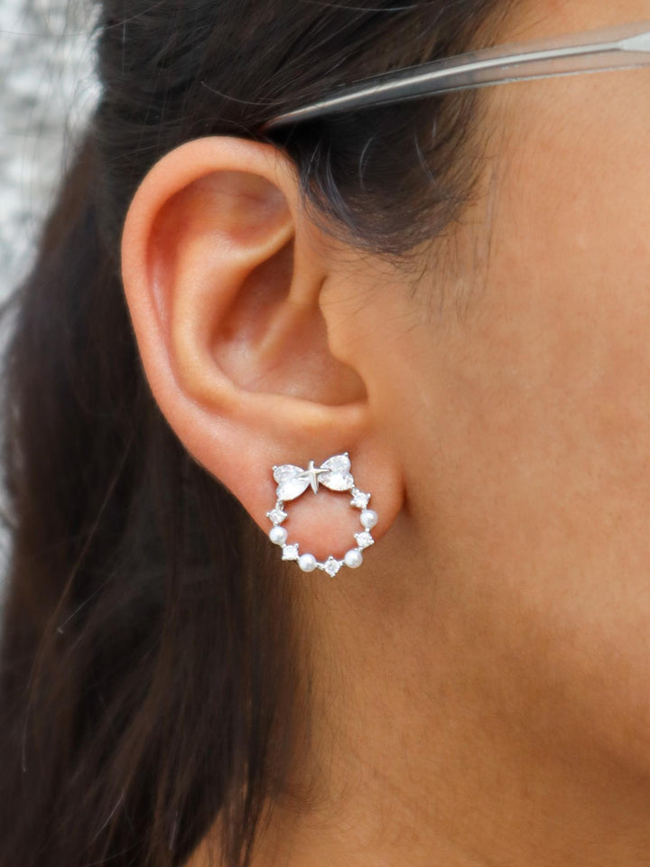 A closeup image of a girl wearing Heart Bow Holy Earrings  by Live Some India 