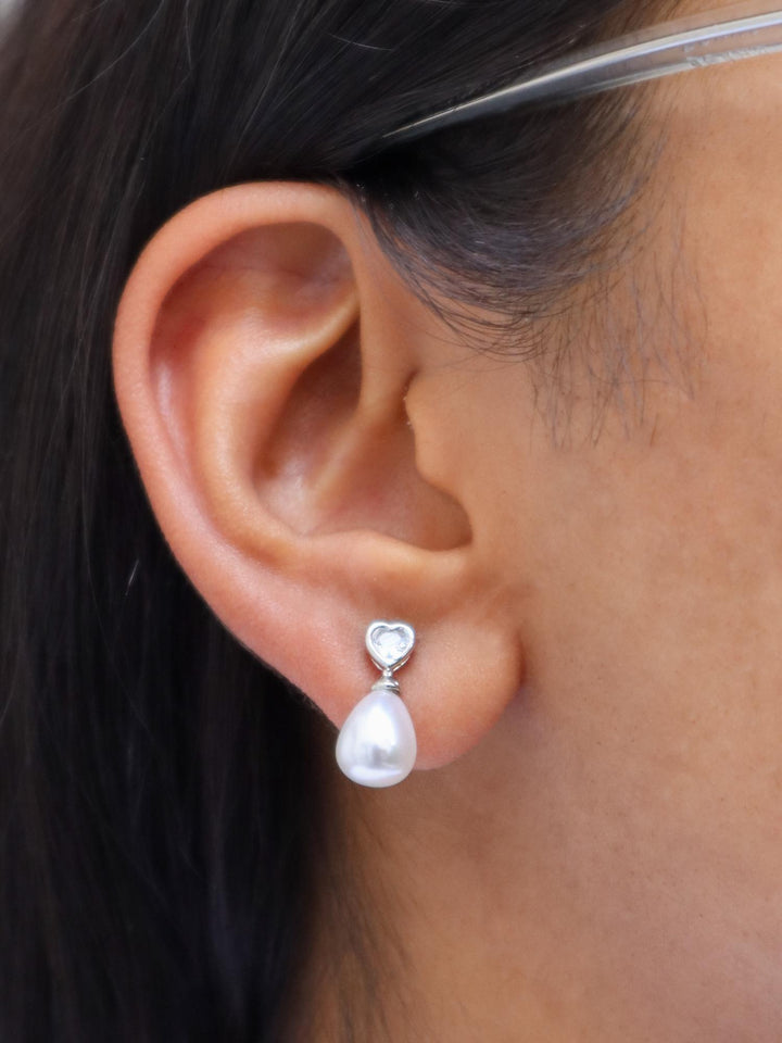 A closeup image of a girl wearing Heart Drop Earrings by Live Some India 