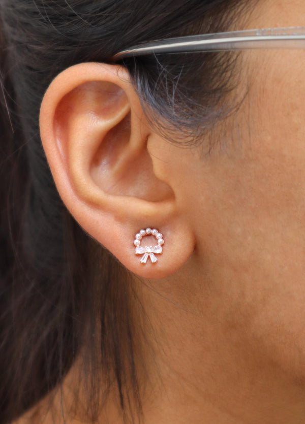 A closeup image of a girl wearing Inverted Bow with Pearl Earrings by Live Some India 