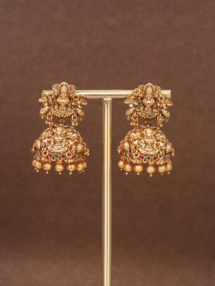 Laxmi Mata Big Jhumka Temple Earrings by Live Some India on an earring stand with brown background