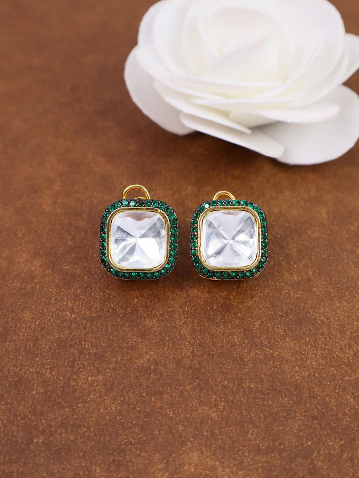 A closeup image of Nia Green Kundan Polki Stud Earrings by Live Some India on a brown background with a white rose