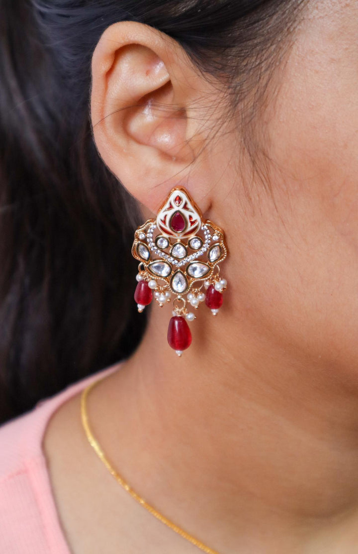 A closeup image of a girl wearing Nia Kundan Polki Red Pendant Earrings by Live Some India