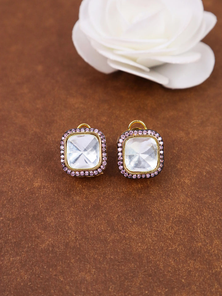 A closeup image of Nia Purple Kundan Polki Stud Earrings by Live Some India on a brown background with a white rose