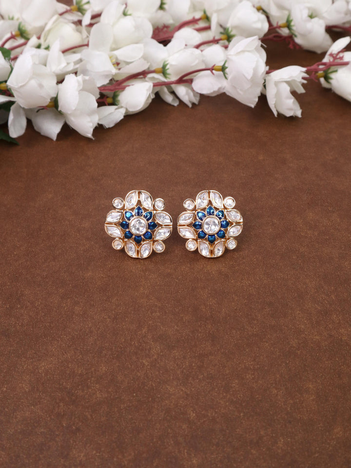 A closeup image of Niu Meenakari Blue Kundan Polki Stud Earrings by Live Some India on a brown background