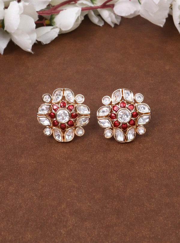 A closeup image of Niu Meenakari Red Kundan Polki Stud Earrings by Live Some India on a brown background 