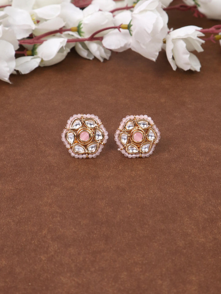 A closeup image of Niva Beaded Pink Kundan Polki Stud Earrings by Live Some India on a brown background 