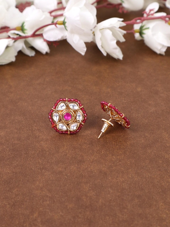 A closeup image of Niva Kundan Polki Red Stud Earrings 1 by Live Some India on a brown background with flowers