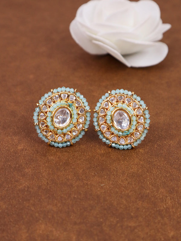 A closeup image of Oval Dainty Kundan Polki Stud Earrings by Live Some India on a brown background with a white rose