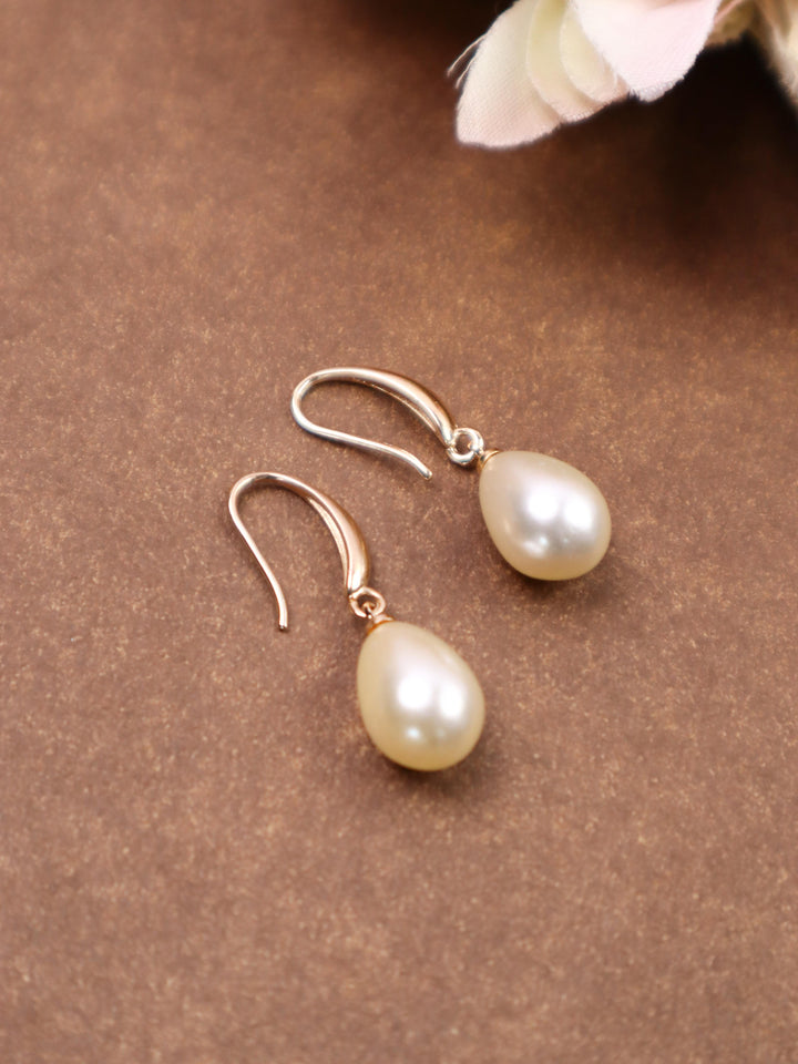 A closeup image of Pearl Drop Earrings by Live Some India on a brown background 