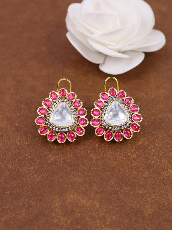 A closeup image of Peer Red Kundan Polki Stud Earrings by Live Some India on a brown background with a white rose