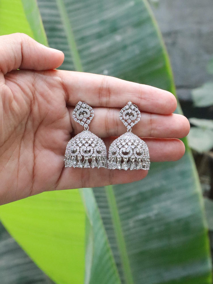 Purva Diamond Jhumka Earrings by Live Some India on hands with natural green leave background