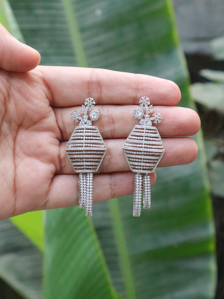 Raya Diamond Dangle Earrings by Live Some India on hand with natural green leaves background