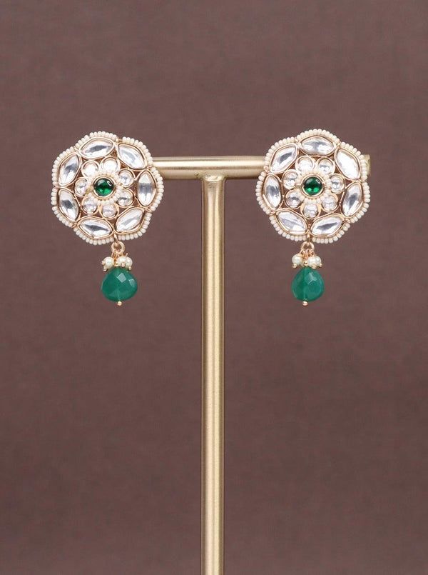 A closeup image of Rekha Green Kundan Polki Dangler Earrings by Live Some India on a brown background 