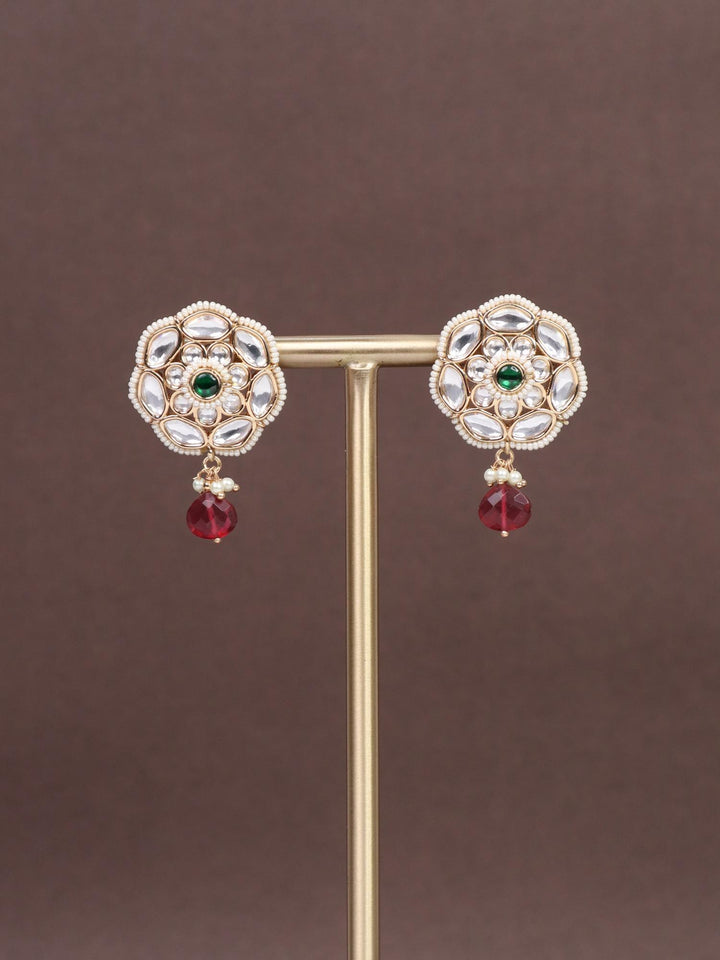 A closeup image of Rekha Red Kundan Polki Dangler Earrings by Live Some India on a brown background 