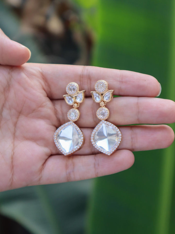 Rhea Designer Kundan Polki Dangle Earrings by Live Some India on hands with natural leaves background