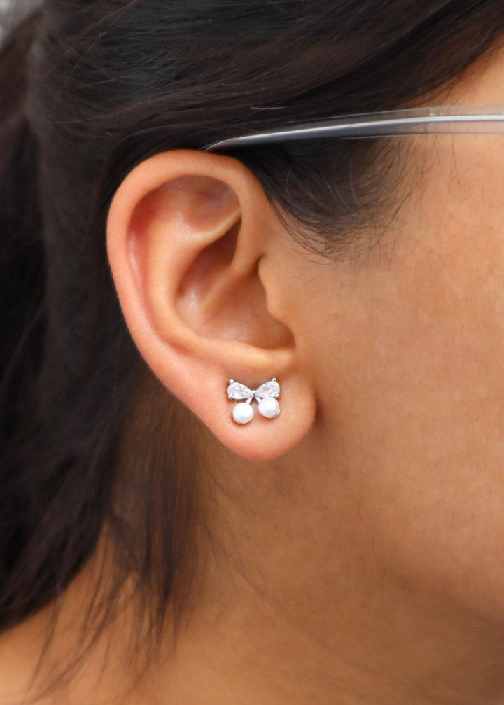 A closeup image of a girl wearing Ribbon Pearl Earrings by Live Some India