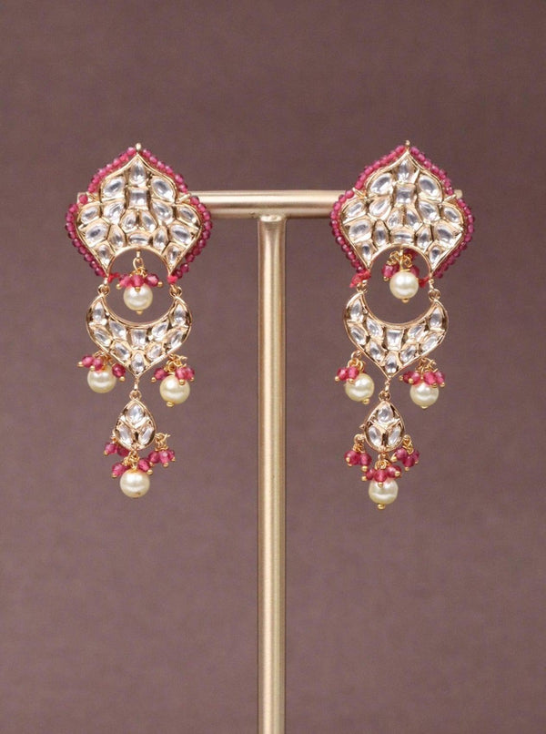 A closeup image of Ritu Kundan Polki Dangler Earrings by Live Some India on a brown background