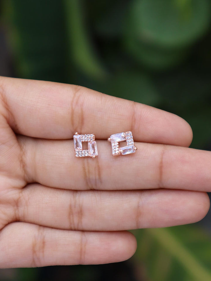 A closeup image of Rose Gold Squared Earrings -1 on a girl's hand by Live Some India