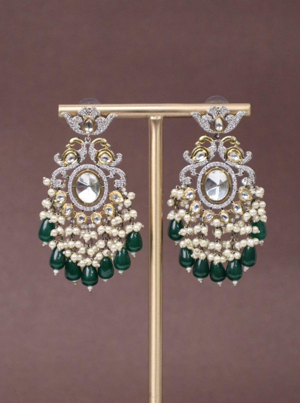 A closeup image of Royal Chic Green Kundan Polki Dangler Earrings by Live Some India on a brown background 