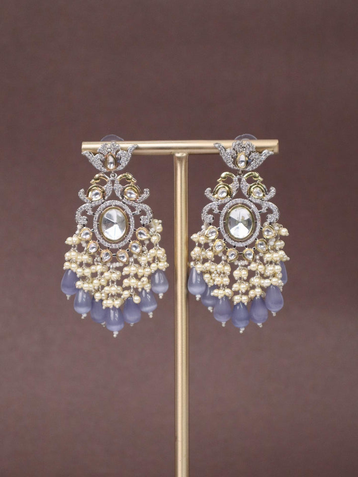 A closeup image of Royal Chic Lilac Kundan Polki Dangler Earrings  by Live Some India on a brown background 