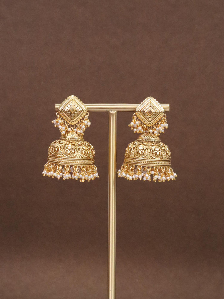 Saavi Temple Jhumka Earrings by Live Some india on a earring stand with brown background