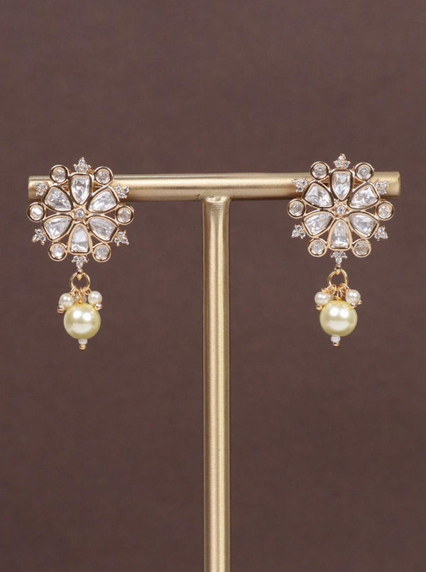 A closeup image of Saavi White Pearl Kundan Polki Earrings by Live Some India on a brown background 