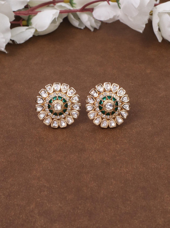 A closeup image of Satvi Green Kundan Polki Stud Earrings by Live Some India on a brown background 