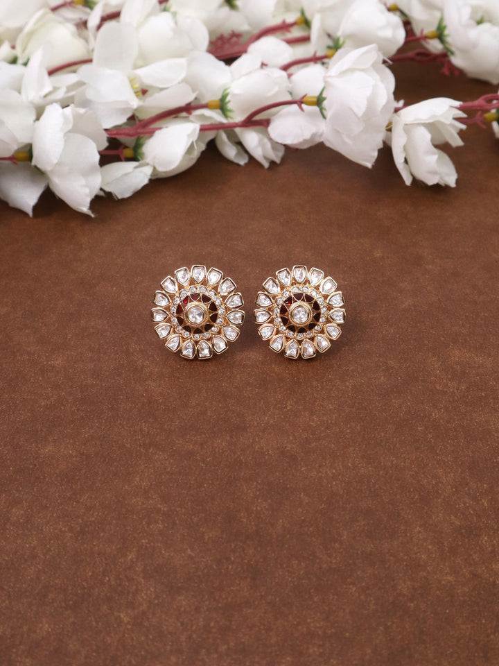 A closeup image of Satvi Red Kundan Polki Stud Earrings by Live Some India on a brown background 