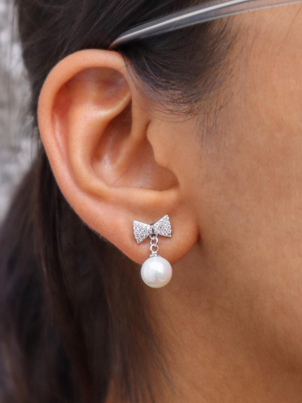 A closeup image of Shimmer Bow with a Pearl Earrings by Live Some India 