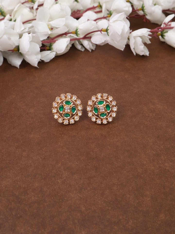 A closeup image of Siya Green Kundan Polki Stud Earrings by Live Some India on a brown background 