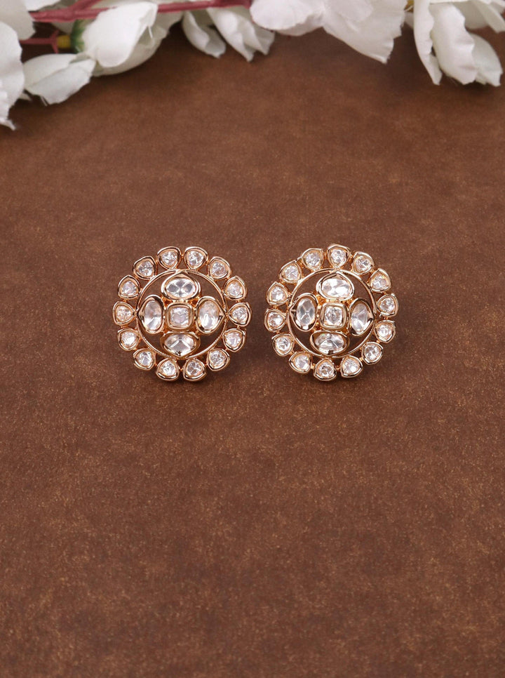 A closeup image of Siya White Kundan Polki Stud Earrings by Live Some India on a brown background 