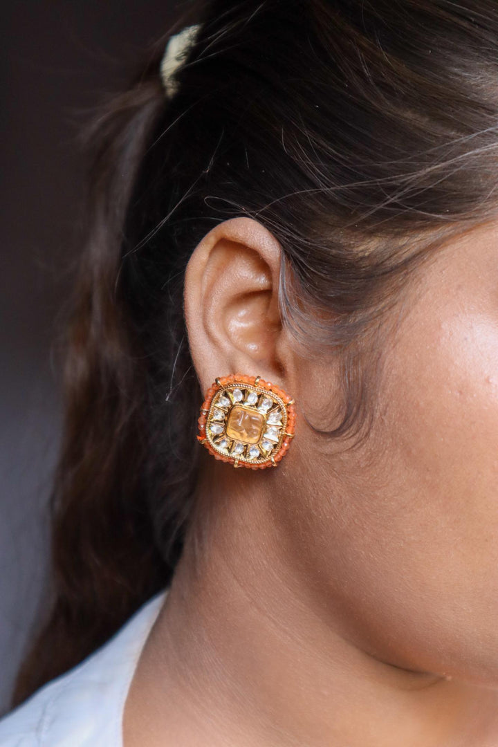 A closeup image of a girl wearing Soft Kundan Polki Orange Stud Earrings -1 by Live Some India 