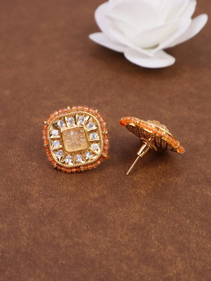 A closeup image of Soft Orange Kundan Polki Stud Earrings 1 by Live Some India on a brown background with a white rose