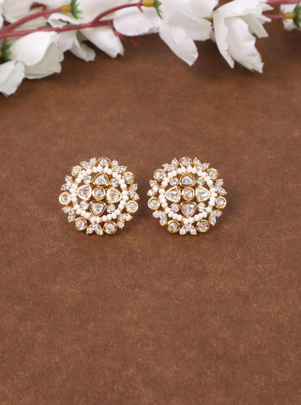 A closeup image of Soni Kundan Polki White Stud Earrings by Live Some India on a brown background with flowers 