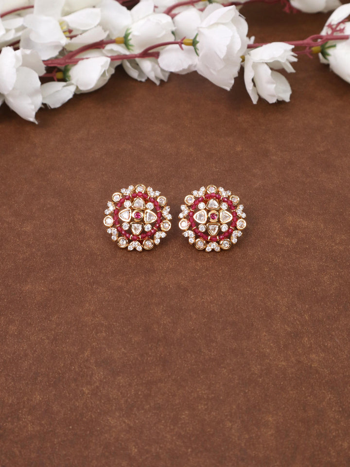 A closeup image of Soni Red Kundan Polki Stud Earrings by Live Some India on a brown background 