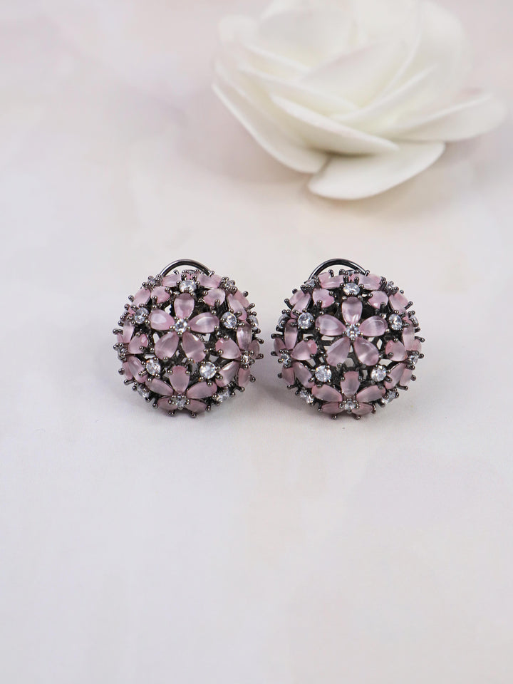 A closeup image of Starry Pink Contemporary Stud Earrings by Live Some India on a white background with a white rose