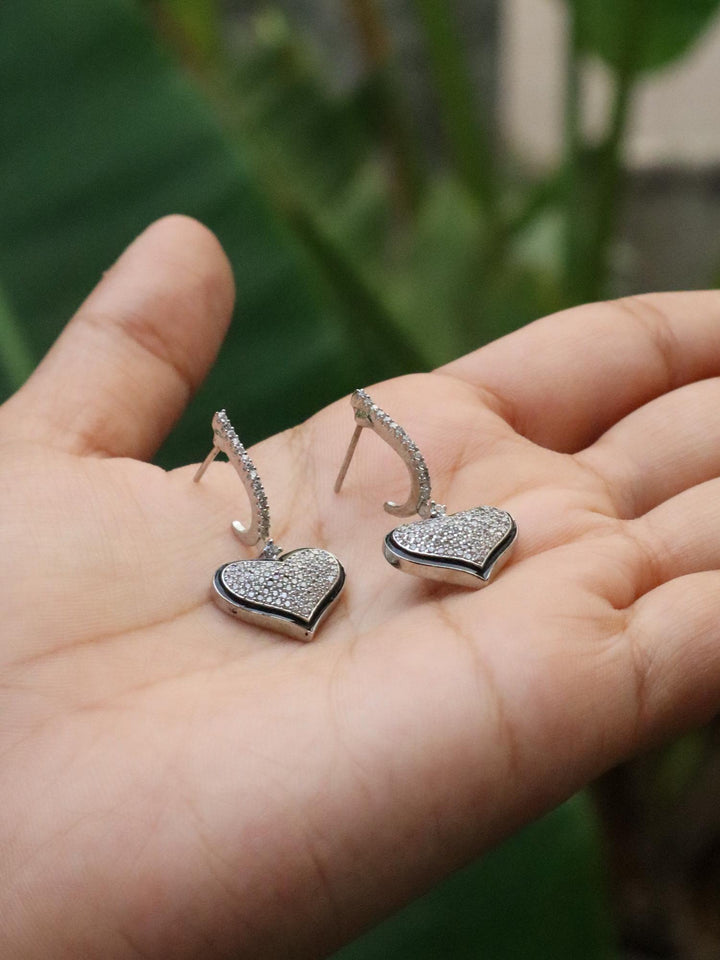 A closeup image of a girl holding Swinging Hearts Dimaond Earrings -2 by Live Some Indi