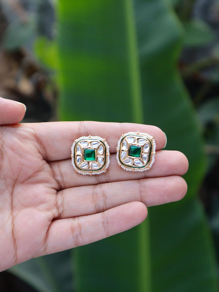 Tanisha Kundan Polki Green Stud Earrings by Live Some India on hands with natural green leaves background