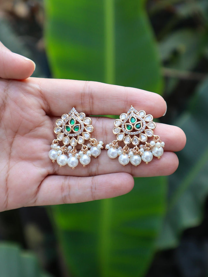 Tia Pearl Drop Kundan Polki Earrings by Live Some India on hands with a green leaves background