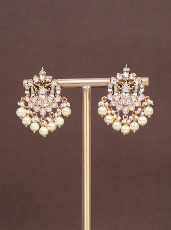 A closeup image of Tia Pearl Kundan Polki Earrings by Live Some India on a brown background