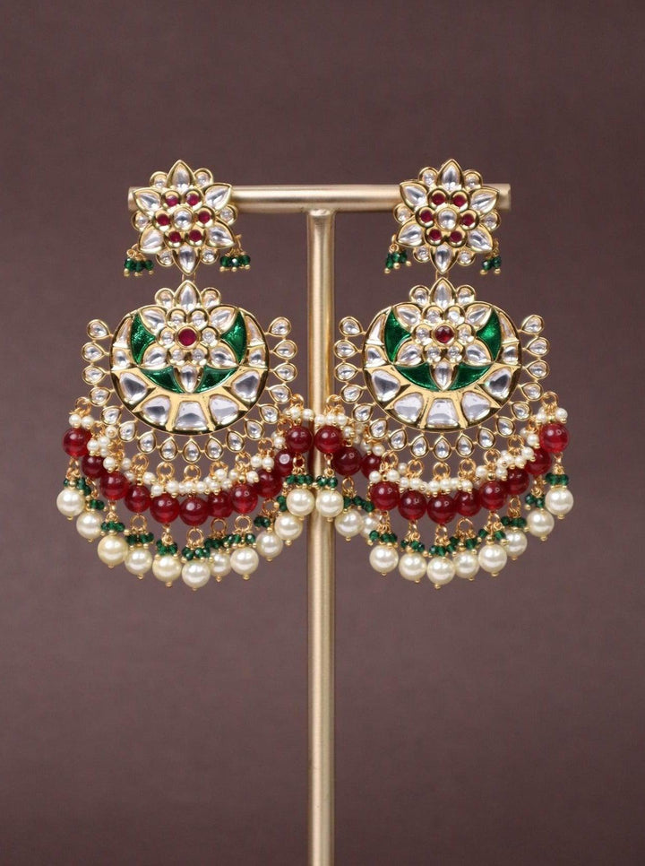 A closeup image of Trendy Red Kundan Polki Chandbali Earrings by Live Some India on a brown background 