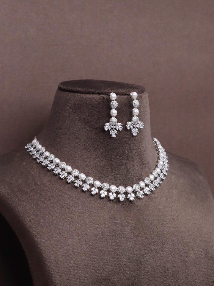 A closeup image of Tulip Silver Pearl Necklace Set by Live Some India on a brown dummy 