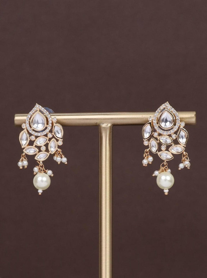 A closeup image of Urja White Pearl Kundan Polki Earrings by Live Some India on brown background 