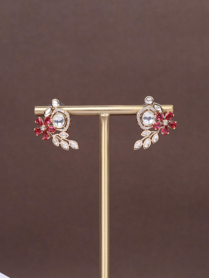 A closeup image of Veena Red Kundan Polki Stud Earrings by Live Some India on a brown background