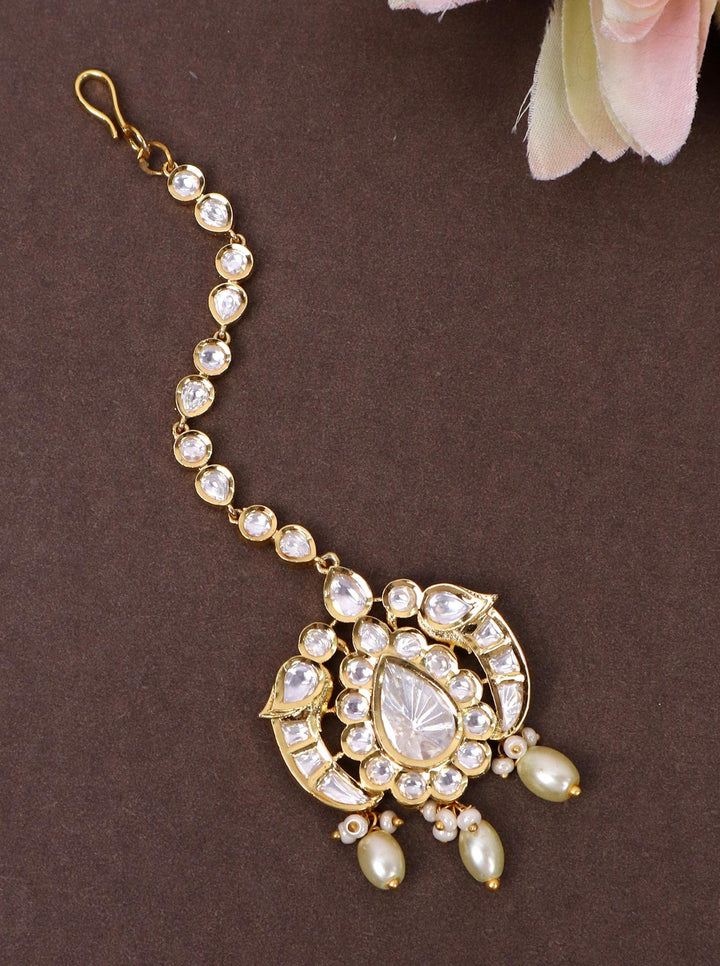 A closeup image of White Kundan Polki Studded Maang Tikka by Live Some India on a  brown background